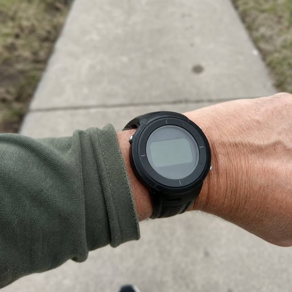 Close-up of a basic step-counter watch on a wrist mid-walk